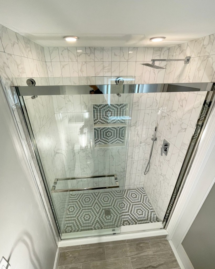 Walk-in shower with a sliding glass door and patterned tile floor