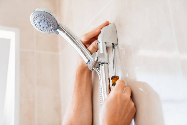 Shower fixtures being installed on a new tiled wall